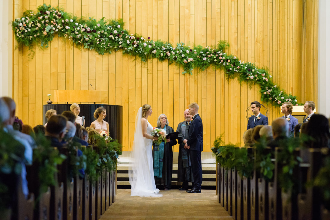 wedding couple in chancel with flowers in the background