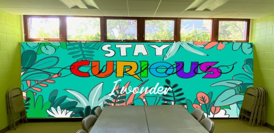 Mock of mural with tropical leaves and words stay curious and I wonder