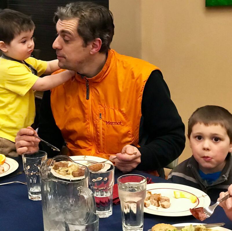Father with two children sitting at dinner table enjoying a shared meal