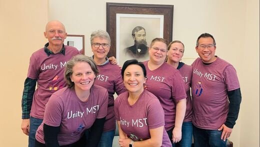 MST members all wearing Unity MST t-shirts and pictured in front of a picture of William Channing Gannett