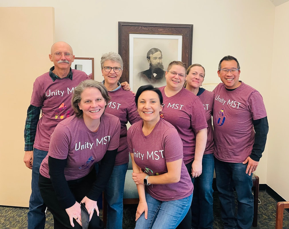 Unity's ministerial search team all wearing matching t-shirts that say Unity MST and standing in front of Rev. Gannett image
